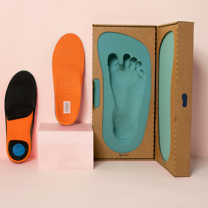 Custom Black and Orange orthotics displayed next to a custom foot mold 