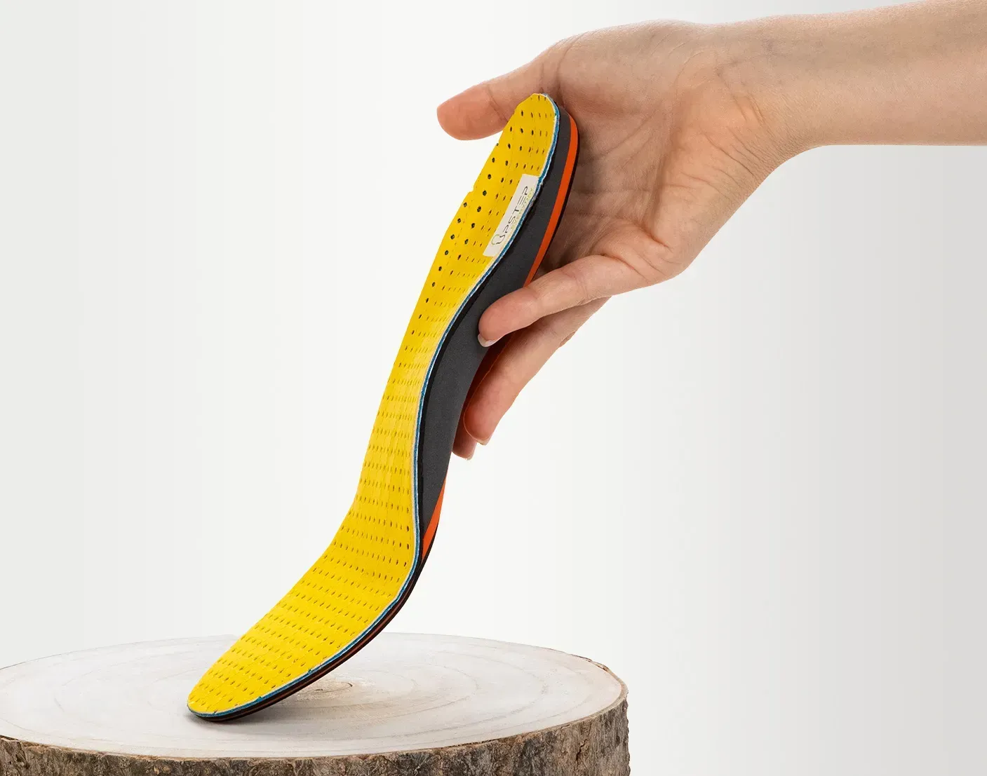 Yellow Upstep custom orthotics for overpronation resting in hand, seen from the side