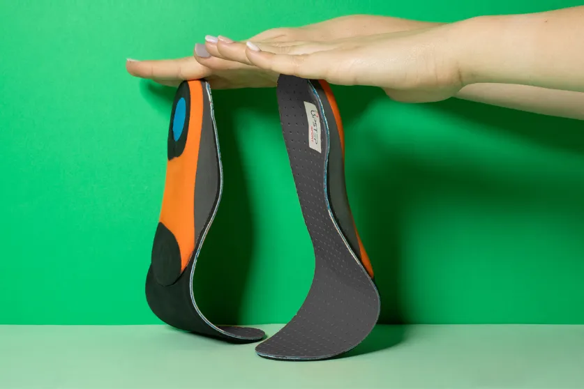 Hands displaying Upstep custom running orthotics vertically