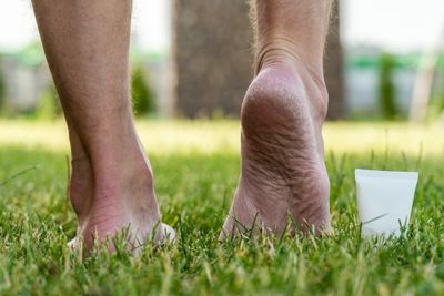 Back of a man's feet standing on grass with one heel raised