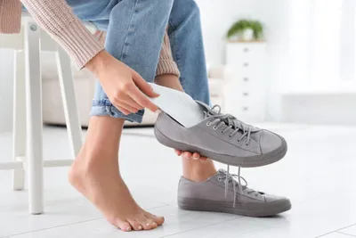 A woman using insoles for her shoes that help correct gait imbalances, among other foot-related issues.