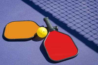 A paddle and ball on the court which is essential amongst other pickleball accessories to enhance your overall performance as a a player