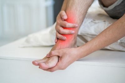 Closeup of man holding ankle with highlighted red inflamed spot