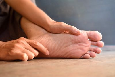 A person inspecting the sole of their foot with both hands 