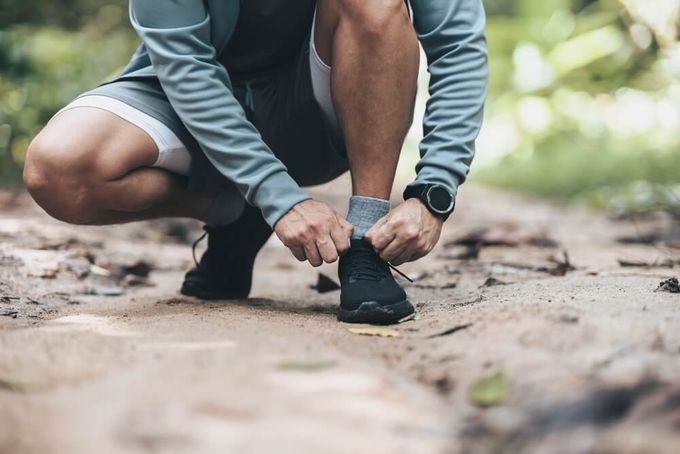 A man tying his sneakers for running—custom insoles are ideal in alleviating pain for runners to correct possible gait abornamlities.