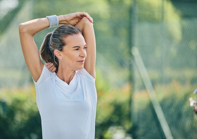 A woman stretching her muscles to prevent pickleball injuries