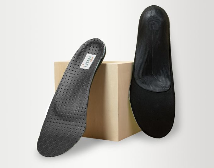 Two black custom insoles from Upstep resting on a box.