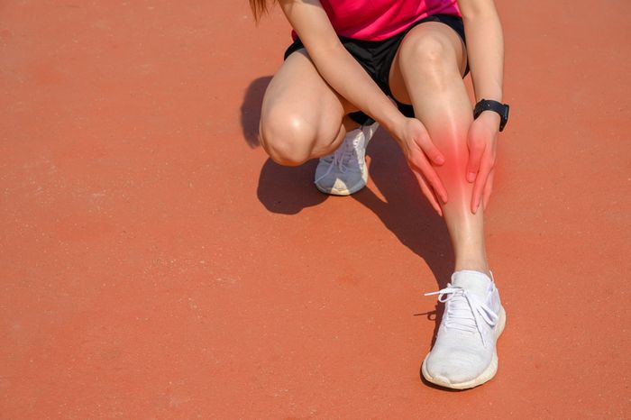 A woman's legs with pain indicated on her shin as she holds it