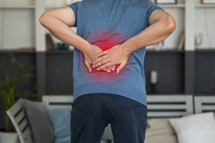 Man hunched over rubbing inflamed spot on lower back