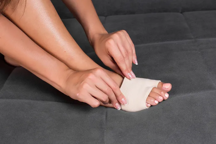 A woman's hands sliding on a gel metatarsal pad to aid treatment of Metatarsalgia
