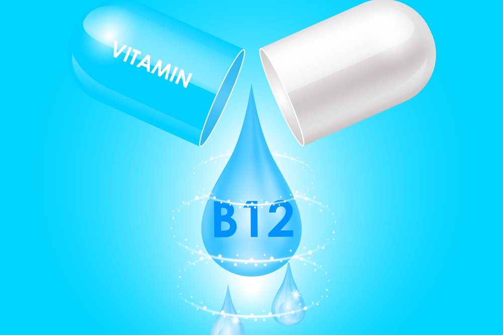 A Vitamin B12 capsule broken open with a water droplet coming out on a blue background