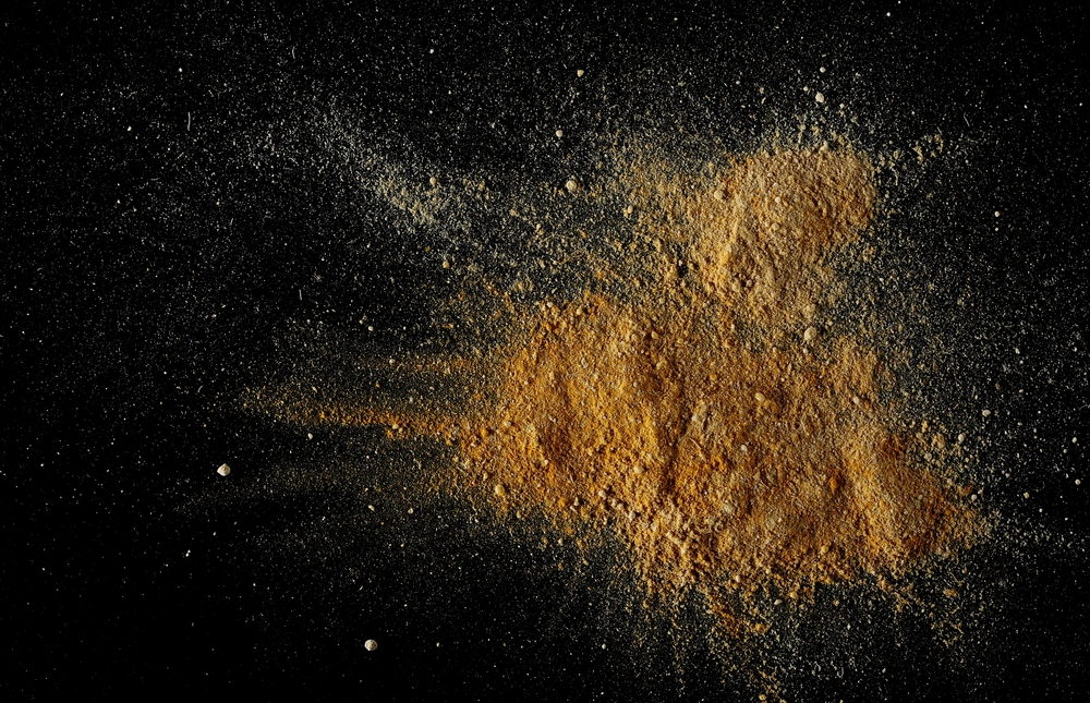 A mix of ginger and turmeric powder on a black tabletop